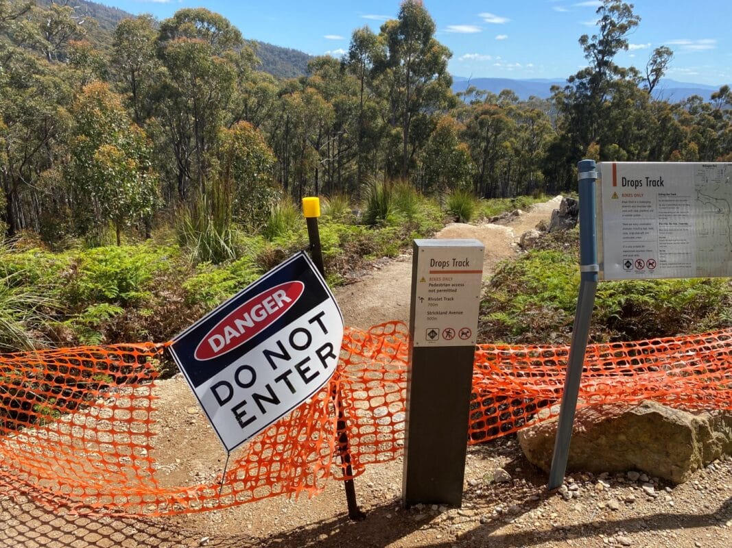 Start of the Drops Track on kunanyi/Mt Wellington shows the plastic fencing torn down and the Don not enter sign hanging off the pole. 